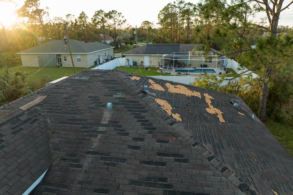 A roof with storm-damaged and missing shingles
