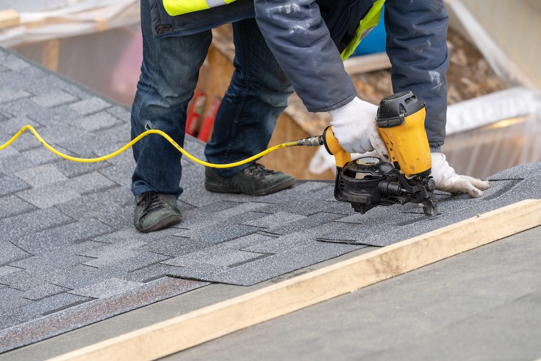 Nailing new shingles during a roof repair