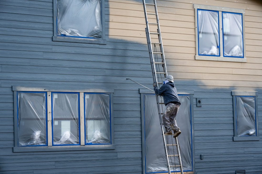 A painter spraying the exterior of a house