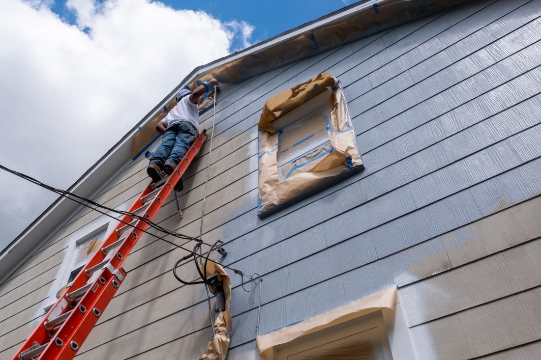 Siding work on a ladder at a home's exterior